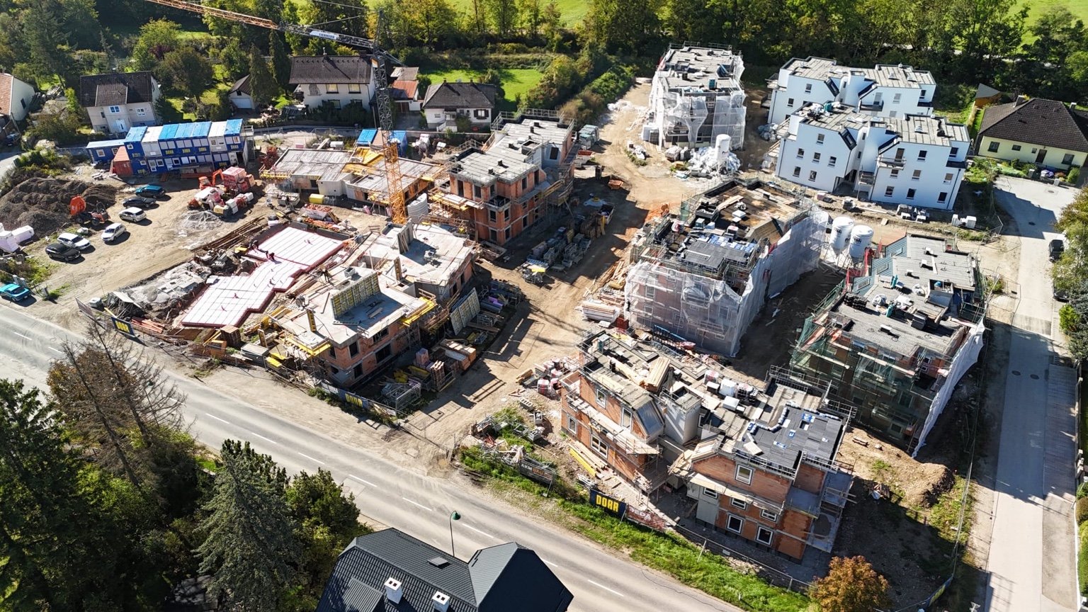 Luftaufnahme einer großen Baustelle in Alland mit mehreren im Bau befindlichen Mehrfamilienhäusern